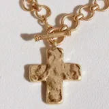 Collar dorado con cadena de eslabones gruesos y dije de cruz con textura irregular.