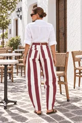 Pantalón de denim con diseño de rayas verticales en colores bordo y blanco, de tiro alto y corte amplio con silueta tipo balloon, bolsillos funcionales y presillas para cinturón.