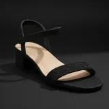 Sandalia de fiesta con taco cuadrado bajo, confeccionada en material con acabado brillante. Presenta una tira frontal ancha y una tira ajustable en el tobillo con cierre de velcro.