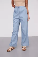 Pantalón celeste de algodón, de tiro alto y corte ancho, con cintura elástica ajustable mediante cordón y aberturas laterales en los bajos.