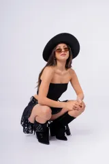 Minifalda negra de encaje con volados y cinturón de cuero sintético con apliques de corazones metálicos.