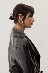 Chaqueta negra de cuero con cuello camisero, mangas largas y costuras decorativas.