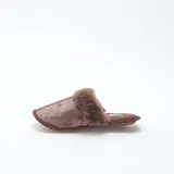 Pantuflas tipo mule color marrón, confeccionadas en material aterciopelado con borde de pelo sintético en la parte superior y suela plana.
