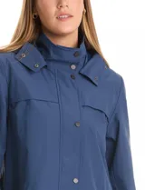 Gabardina impermeable de corte evasé en color azul. Presenta cierre frontal oculto con botones a presión, cuello alto, capucha fija y bolsillos laterales con cierre. Incluye forro interno.