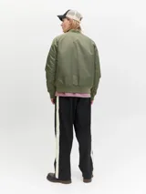 Campera tipo bomber color verde oliva, con cierre frontal de doble dirección, cuello, puños y ruedo acanalados. Presenta bolsillos laterales con solapa y forrería interna.