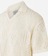 Camisa polo de mangas cortas color crema, confeccionada en tejido de punto calado con cuello inglés.