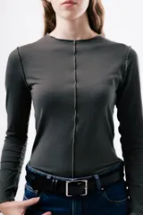 Camiseta de manga larga en color gris oscuro, con cuello redondo y costuras decorativas expuestas en el frente. Presenta un diseño ajustado al cuerpo.