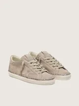 Zapatillas Golden Goose modelo Super-Star en gamuza color topo. Presentan diseño de aspecto desgastado, con la clásica estrella lateral en el mismo tono, contrafuerte metalizado en color bronce, cordones tono sobre tono y detalle de glitter champagne en el canto de la suela.