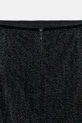 Falda midi de tiro medio, color negro, cubierta de abalorios con detalle de flecos a tono en el bajo.