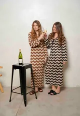 Vestido largo de lurex con diseño de patrón en zigzag en tonos tostado y marrón, escote en V con cordones para atar y mangas largas.