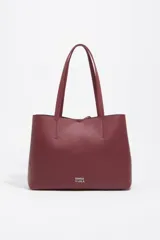 Bolso shopper de piel color borgoña, con textura granulada, asas de hombro y cierre de cordón. Presenta el logo metálico de Bimba y Lola en el frente.