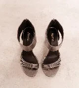 Sandalias de tacón alto en color negro, confeccionadas en 100% cuero vacuno. Presentan un diseño elegante con tiras finas en la parte delantera y una pulsera ancha en el tobillo con cierre de cremallera en la parte trasera. Cuenta con un taco ancho.