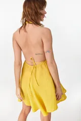 Vestido corto color amarillo de lino italiano, con escote halter cruzado en V pronunciado y cintura elastizada fruncida con falda amplia y voluminosa.
