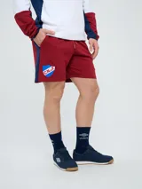 Bermuda deportiva Umbro del Club Nacional de Football, color azul marino, con cordón ajustable en la cintura, bolsillos laterales, el escudo del club en una pierna y el logo de la marca en la otra.