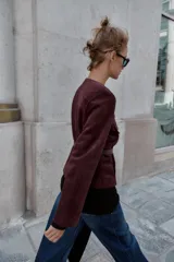 Blazer de cuello redondo y manga larga, confeccionado en tejido efecto ante. Presenta cierre frontal con botones, bolsillos con tapeta en el pecho y cinturón ajustable en la cintura.