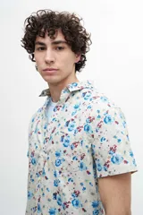 Camisa de manga corta confeccionada en tela 100% algodón con estampado de cachemir en tonos naranja y celeste. Tiene un bolsillo en el pecho y botones personalizados.