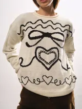 Buzo de cuello redondo con calce holgado, confeccionado en tejido de punto grueso con diseño jacquard de moña y corazones en contraste.