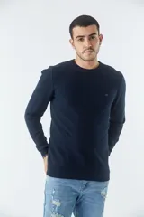 Sweater de punto con textura geométrica, color gris, de cuello redondo y manga larga. Presenta puños y ruedo acanalados con detalle de borde en color oscuro y logo bordado en el pecho.