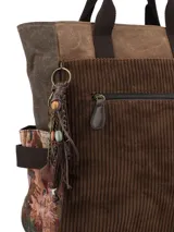 Mochila de diseño patchwork en tonos marrones, confeccionada en una combinación de pana, tela encerada y tejido estampado. Cuenta con manijas superiores fijas, bolsillo frontal con cierre, compartimento principal con cierre y detalles de borlas decorativas en el lateral.
