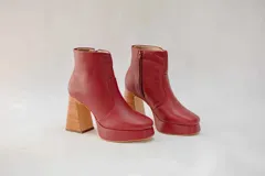 Botas cortas de cuero color rojo con plataforma y taco cuadrado de madera. Cierre lateral con cremallera.