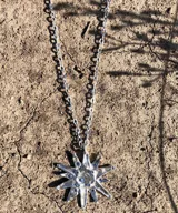 Collar con cadena fina negra y dije de estrella plateada con incrustaciones de strass.