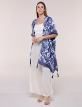 Kimono de gasa ligera con estampado floral en tonos de azul y blanco, silueta amplia, mangas cortas y detalle de borlas en el ruedo asimétrico.