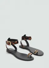 Sandalia plana con diseño de dedo, confeccionada en piel bovina con pelo y estampado de leopardo. Cuenta con una tira tobillera ajustable mediante hebilla metálica dorada y un detalle metálico en el anillo del dedo.