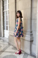 Vestido corto sin mangas de corte recto y holgado, confeccionado en lino con estampado floral multicolor sobre fondo azul oscuro. Presenta cuello redondo y cierre posterior con botones forrados.