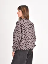 Buzo de cuello redondo y manga larga con estampado animal print de leopardo en tonos beige, marrón y negro. Presenta un corte holgado y puños y ruedo acanalados.