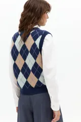 Chaleco de punto color azul marino con estampado de rombos en tonos beige, azul claro y lila. Tiene escote en V, botones frontales y terminaciones de rib.