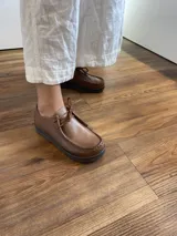 Zapato acordonado color marrón claro, de cuero, con suela de goma negra.