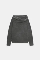 Jersey de punto color gris oscuro, con escote recto tipo off-shoulder, manga larga y detalle de aplique metálico en el hombro. Presenta acabados en rib en puños y ruedo.
