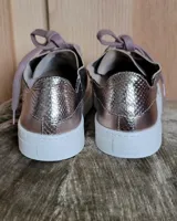 Zapatillas plateadas de cuero con cordones grises y suela blanca.