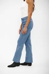 Jean de corte recto y tiro medio, color azul medio, con diseño clásico de cinco bolsillos y ruedo deshilachado.