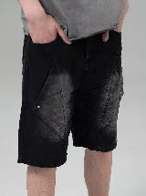 Bermuda de denim con diseño de paneles geométricos y efecto lavado desgastado. Presenta un corte regular fit con detalles de remaches metálicos en los laterales.