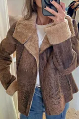 Campera tipo gamulán de cuero genuino en color marrón con efecto desgastado. Presenta interior y solapas de piel sintética en tono tostado, cierre frontal cruzado y puños con vuelta de piel.