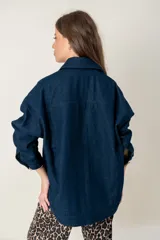 Campera de jean oversize en color azul oscuro, con corte recto, cuello camisero, cierre frontal con botones y bolsillos frontales tipo parche.