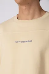 Remerón de corte oversized confeccionado en tejido rústico, con cuello redondo y mangas cortas. Presenta un diseño minimalista con una pequeña estampa frontal centrada en el pecho.