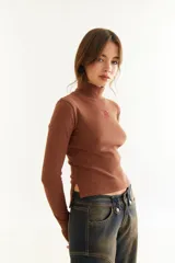 Top de manga larga con cuello alto, confeccionado en tejido de lycra y algodón. Presenta costuras a contratono, bordado central en el pecho, aberturas laterales en el ruedo y diseño con dedal en las mangas.