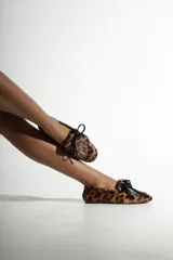 Mocasín Schutz de estilo marinero con estampado de leopardo, confeccionado en cuero con textura de pelo. Presenta detalle de flecos y lazo decorativo en el empeine.