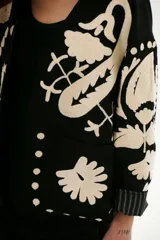 Chaqueta color crudo con bordados florales en tonos rojo, verde y negro.