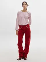 Pantalón de pana roja con corte holgado y tiro medio. Presenta una línea dorada a lo largo de la pierna.