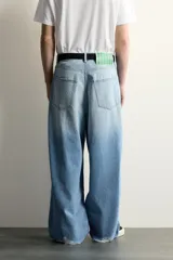 Jeans baggy fit de corte holgado en denim de algodón celeste, con tiro medio, cinco bolsillos, roturas en las rodillas y cierre frontal con cremallera y botón.
