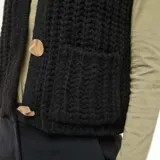 Chaleco de punto grueso color negro, sin mangas, con cuello redondo y cierre frontal con botones dorados.