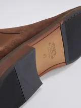 Bota Chelsea de gamuza gris con elásticos laterales, suela de goma marrón y tirador trasero.