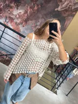 Blusa de encaje calado en color off-white con diseño de flores pequeñas, corte holgado, escote redondo y mangas tres cuartos.