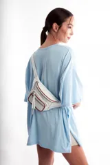 Riñonera color beige con textura de piel de cocodrilo, correa ajustable y cierre con cremallera.