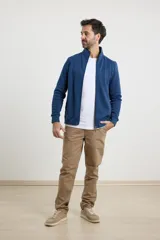 Cardigan de tejido de punto color verde militar, con cierre frontal de metal y cuello redondo. Presenta detalle de tejido plano en la cartera del cierre y en los bolsillos laterales.