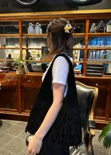 Cartera bandolera negra de gamuza con flecos largos en la parte inferior.