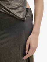 Vestido largo de tejido fino y muy elástico, con acabado metalizado en tonos negro y dorado. Presenta un diseño entallado, escote halter con fruncido y espalda abierta. Incluye un body integrado con cierre de tres corchetes y una abertura lateral alta en la falda.